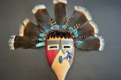 Handcrafted gourd mask with feathered headdress by Donna Vargas